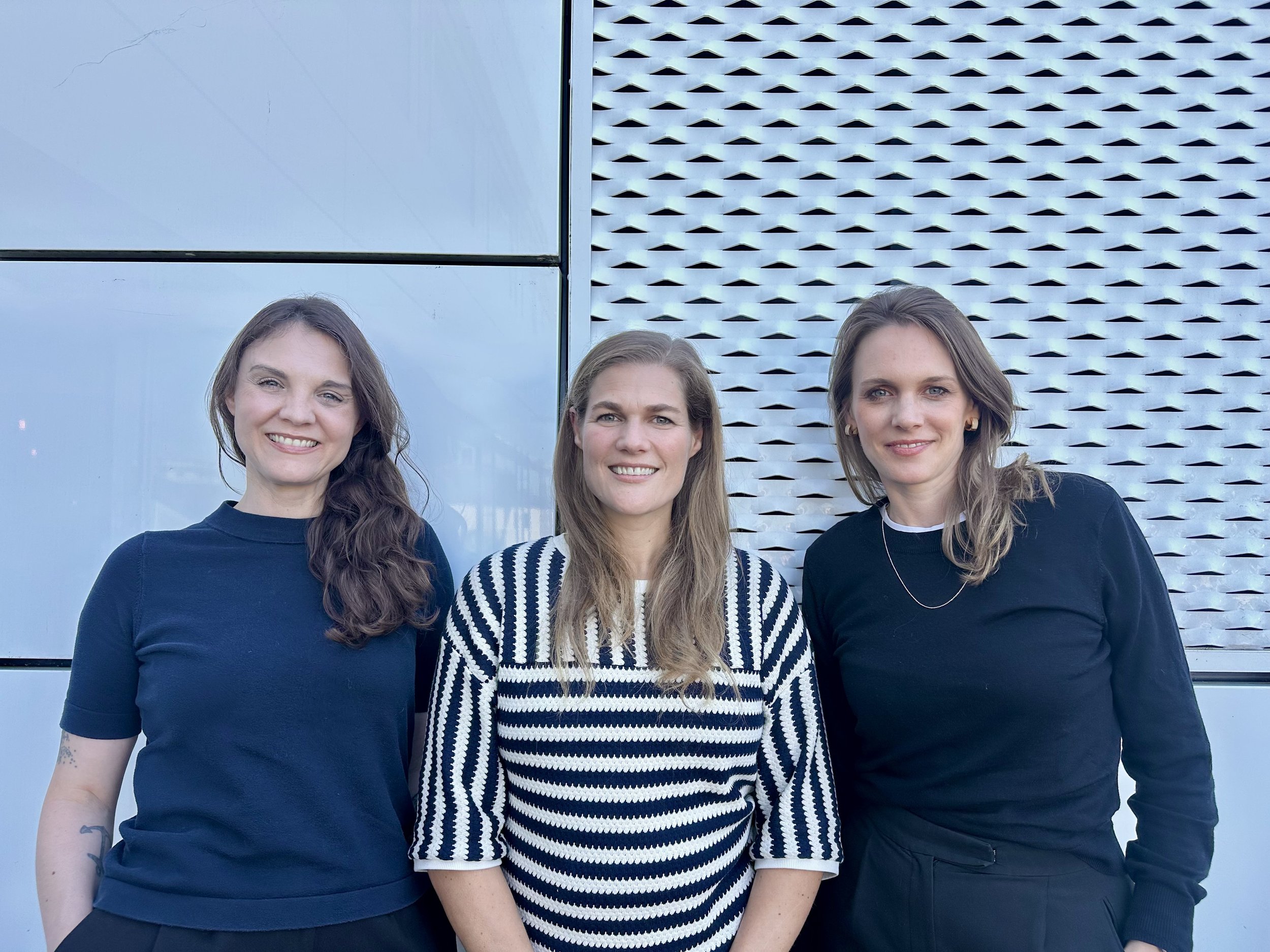 The three Finches co-founders, Stefanie Glenn, Catharina van Delden and Alexandra Vázquez Bea, standing in front of a perforated metal facade