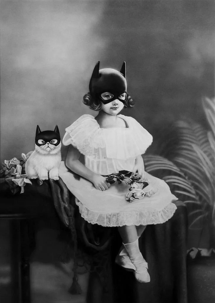 Une jeune fille en robe blanche portant un masque de Batman, assise sur une table avec un chat portant aussi un masque de Batman, style vintage en noir et blanc.