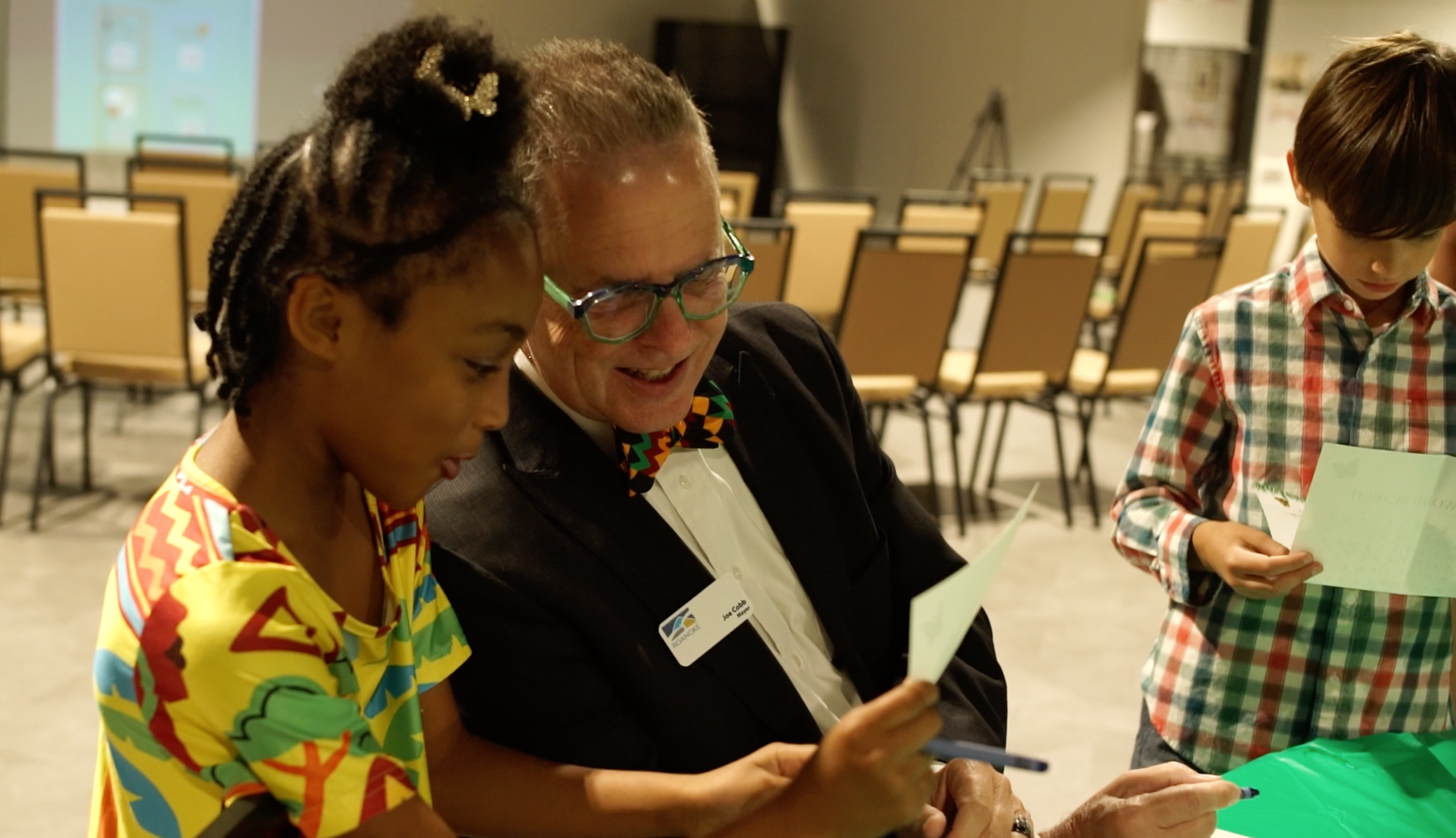 Roanoke Mayor Joe Cobb makes a butterfly craft with a young girl at It's Cool to Learn