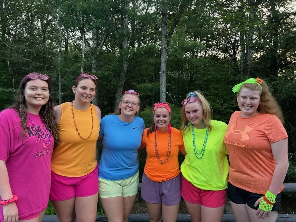 Girls smiling with their camp counselor at a youth event