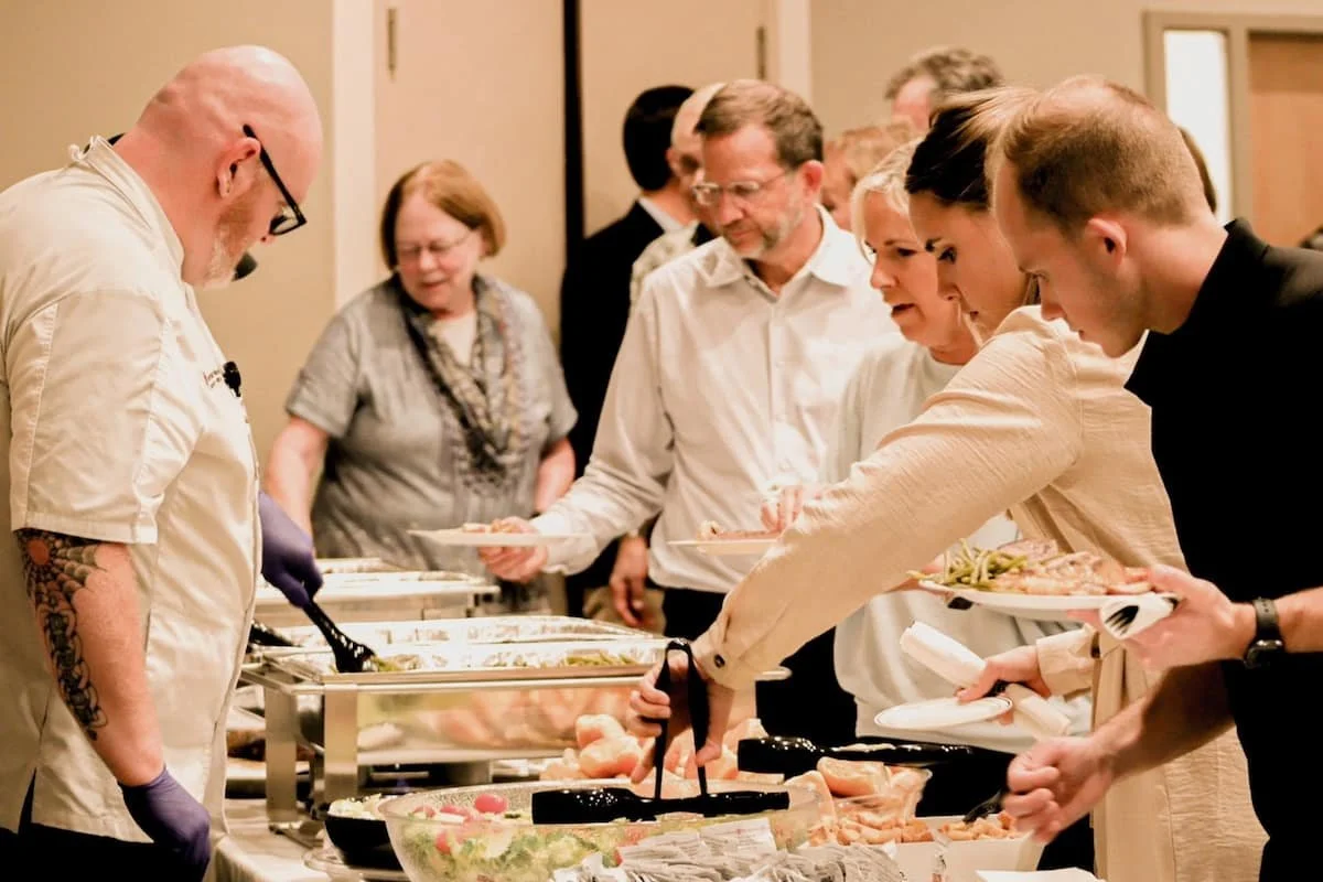 People serving themselves food in a community setting during a fundraiser event.