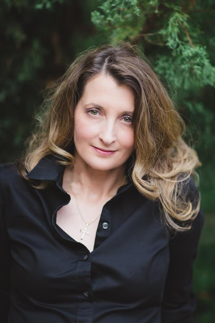 Color portrait of author in black shirt with trees in the background.