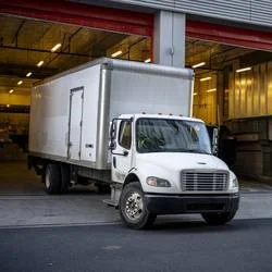 White delivery truck parked outside a warehouse