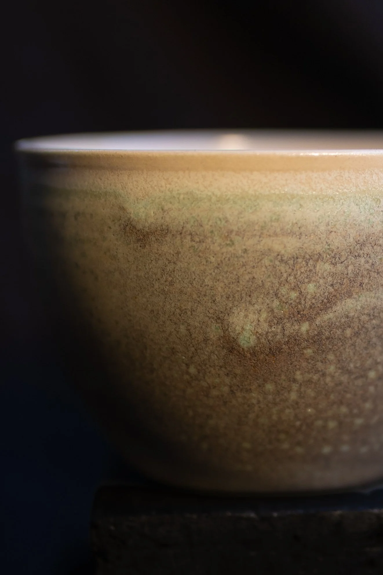 Nahaufnahme einer Keramikschale mit braunem und grünen Glanz auf schwarzem Hintergrund.