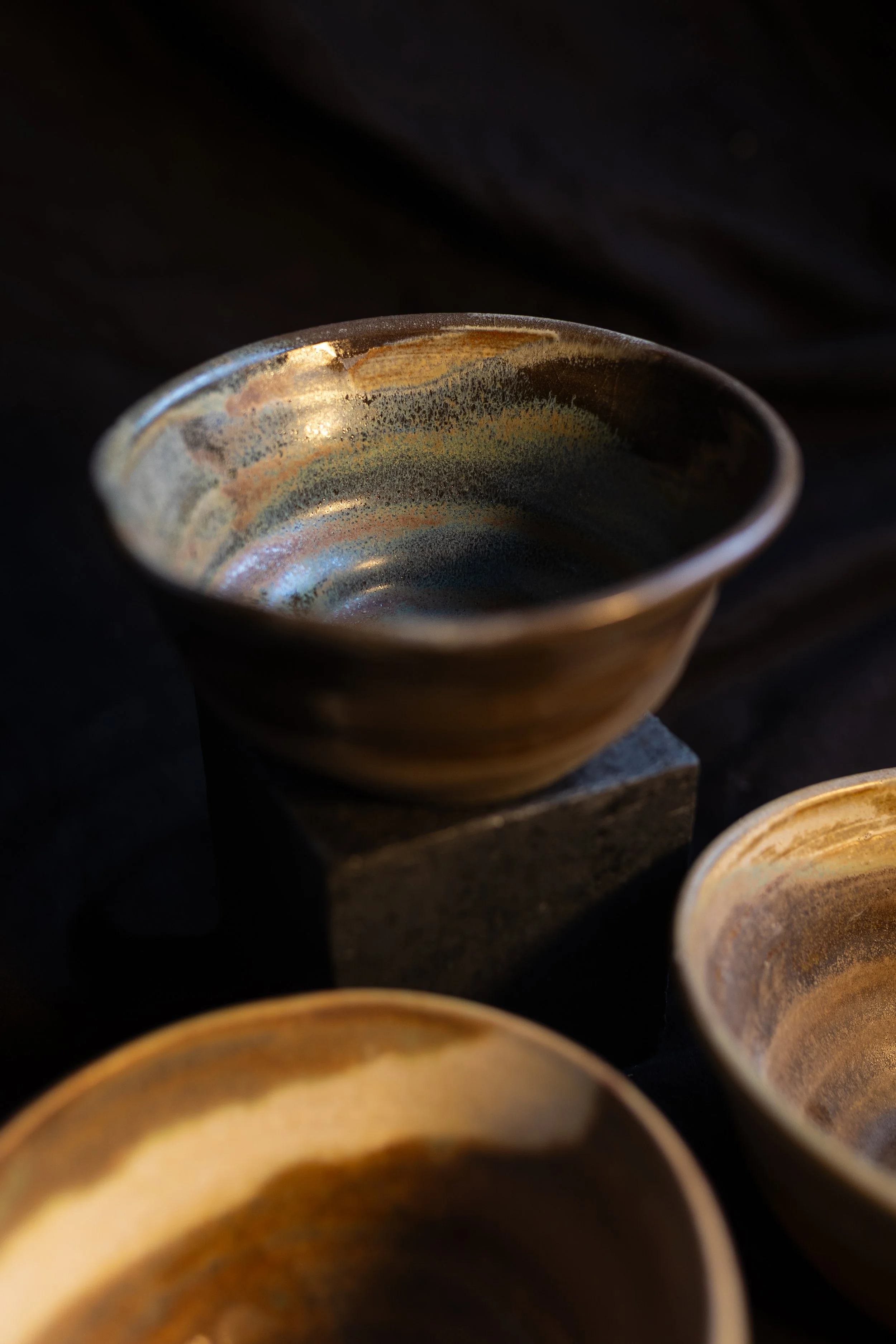 Drei kleine keramische Schalen mit glasiertem Muster auf einem dunklen Hintergrund.