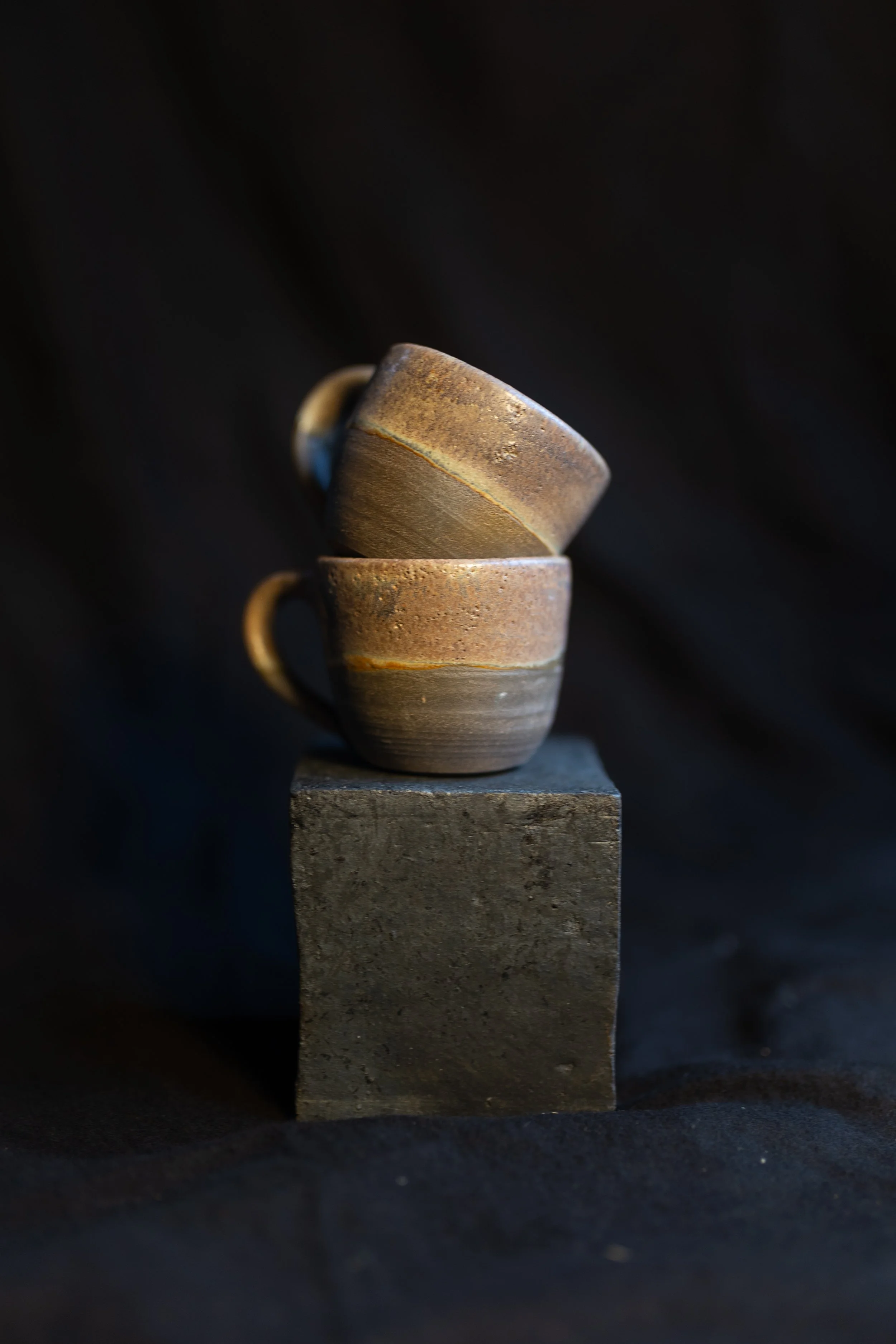 Drei braune Keramiktassen auf einem schwarzen Sockel