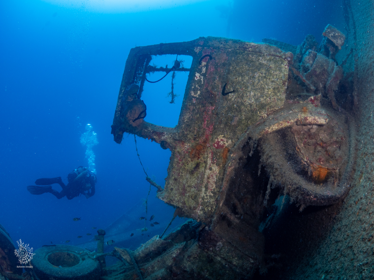 A scuba diver exploring the sunken Zenobia shipwreck underwater.