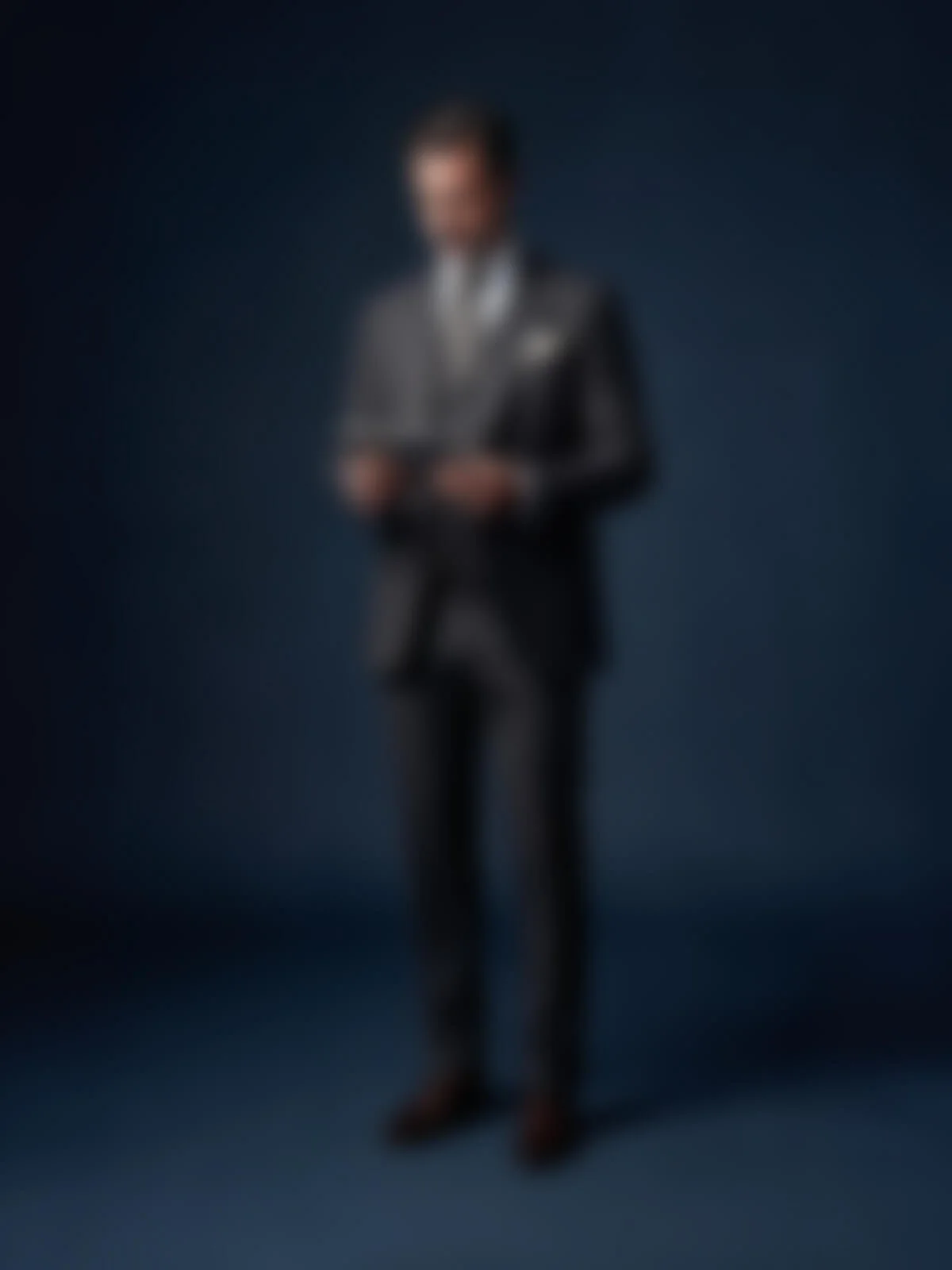 Die Person trägt einen dunklen Anzug und steht vor einem dunklen Hintergrund.