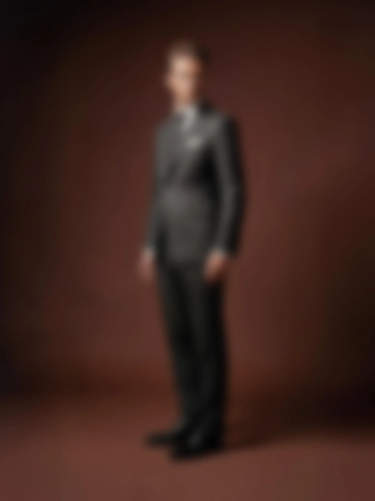 Ein Mensch in einem schwarzen Anzug steht vor einem braunen Hintergrund, das Bild ist unscharf.