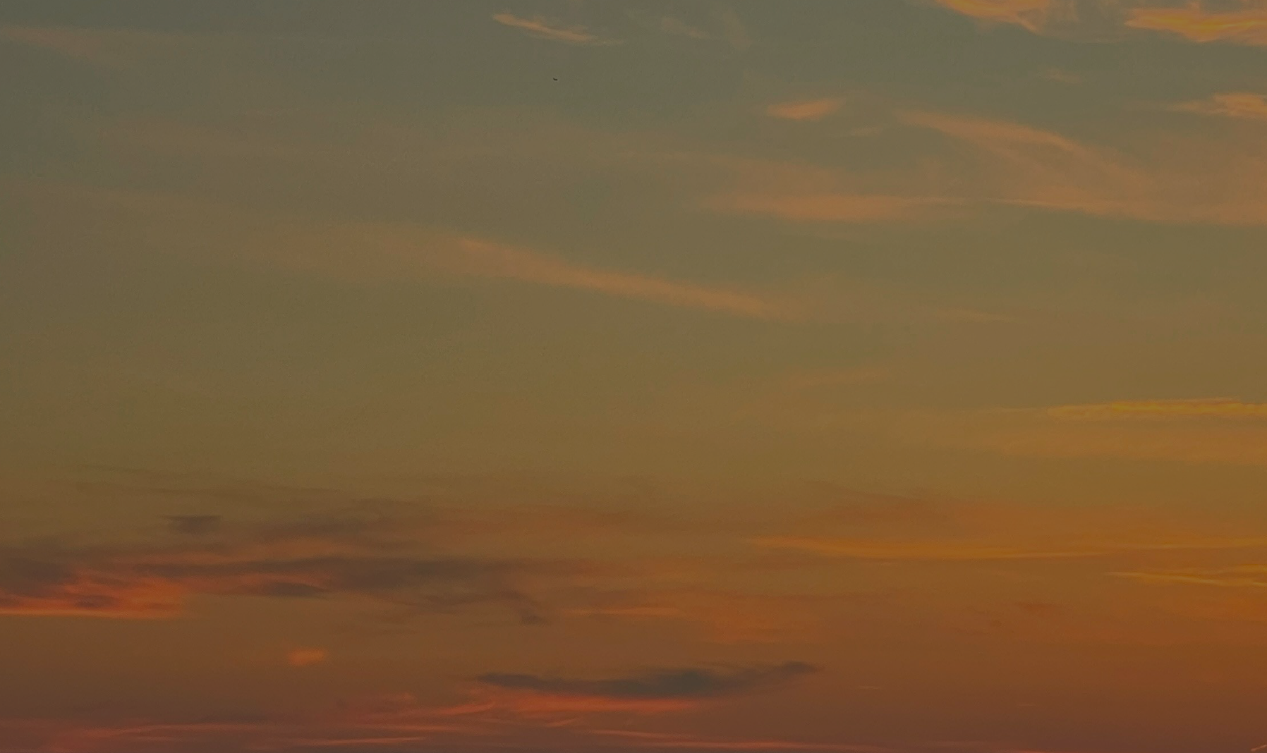 A sunset sky with orange and pink hues and scattered clouds.