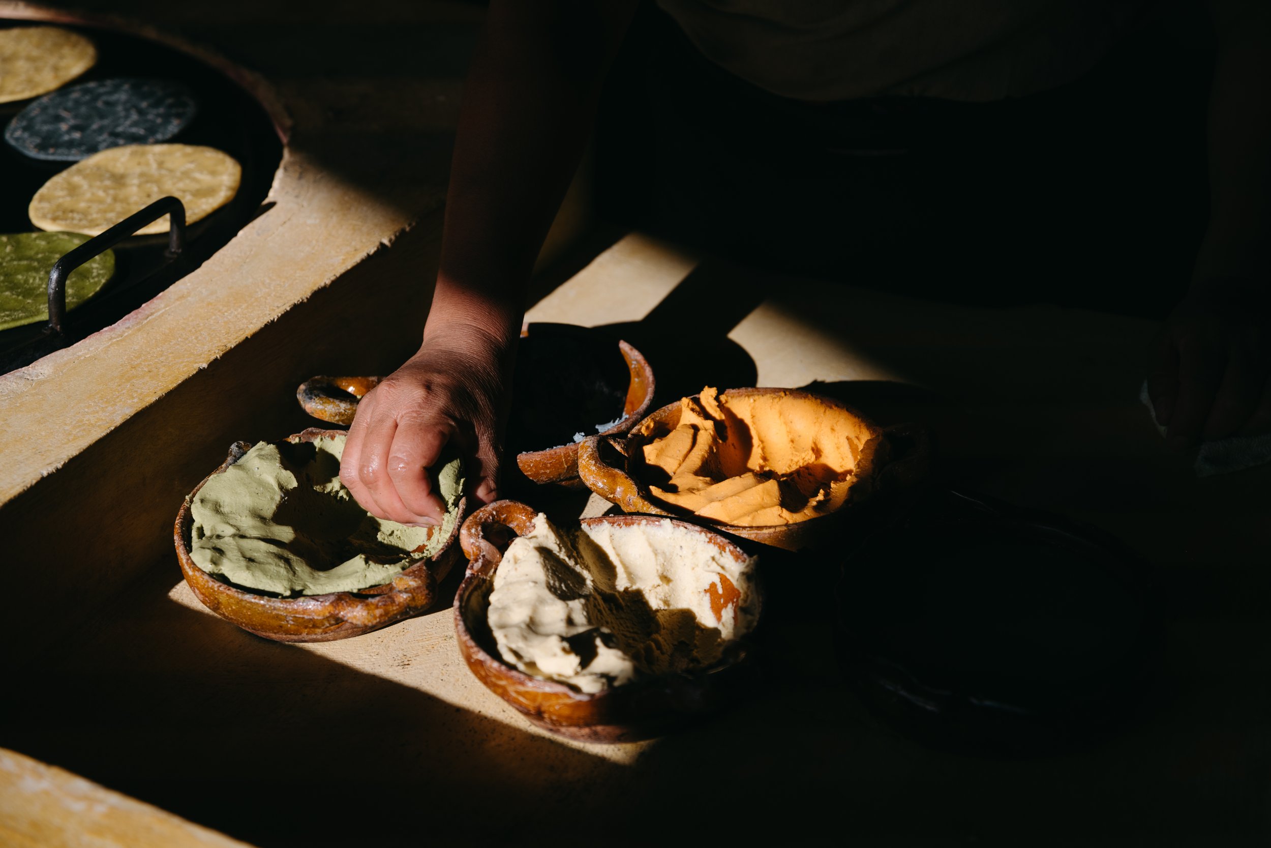 Woman making tortillas with colorful corn at El Comalote in Antigua, Guatemala, captured in a documentary photography session for the brand.