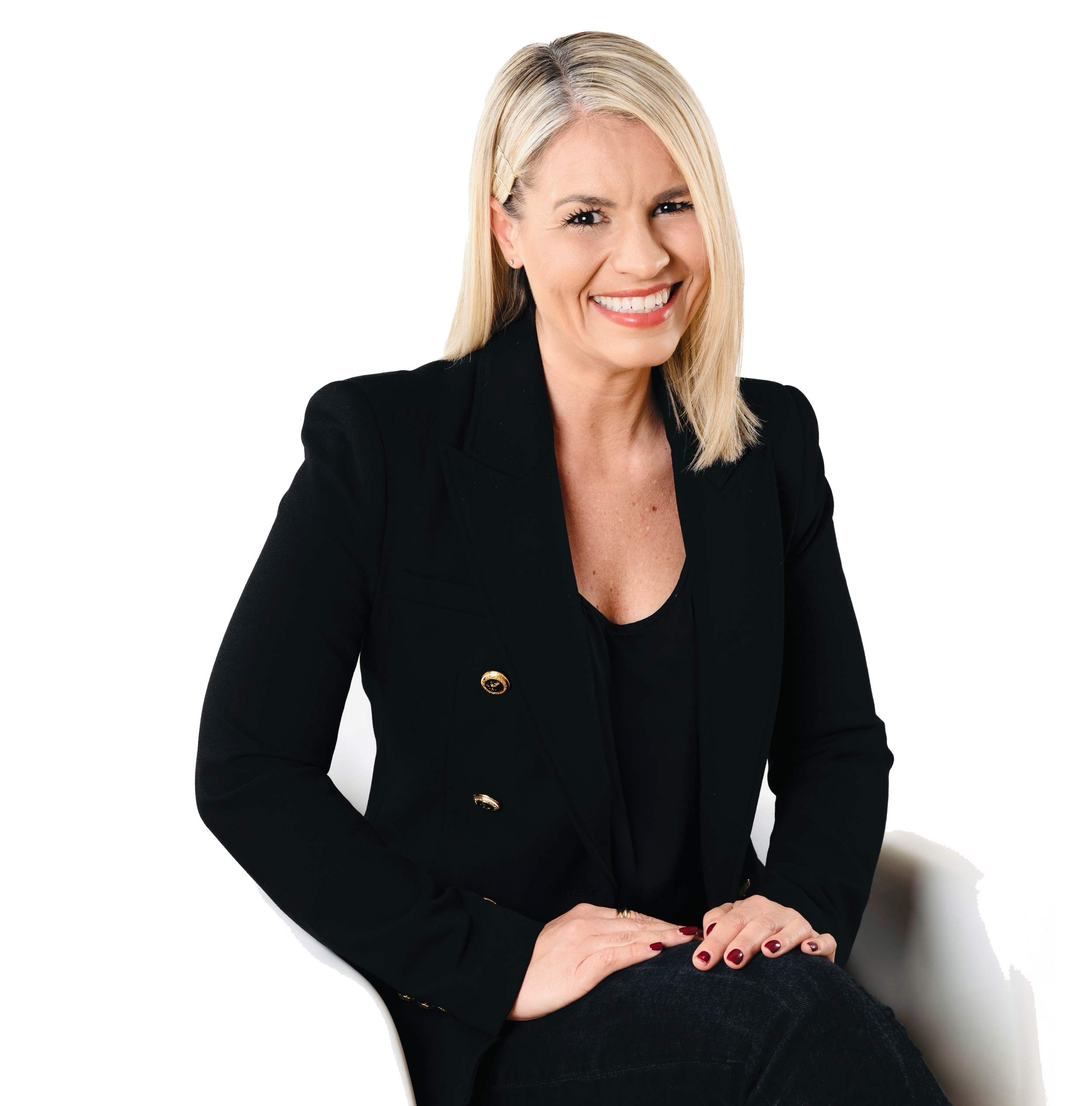 Eine lächelnde blonde Frau in schwarzem Blazer sitzt auf einem Stuhl, vor einem Hintergrund, der zu einem Teil schwarz und zu einem Teil weiß ist.