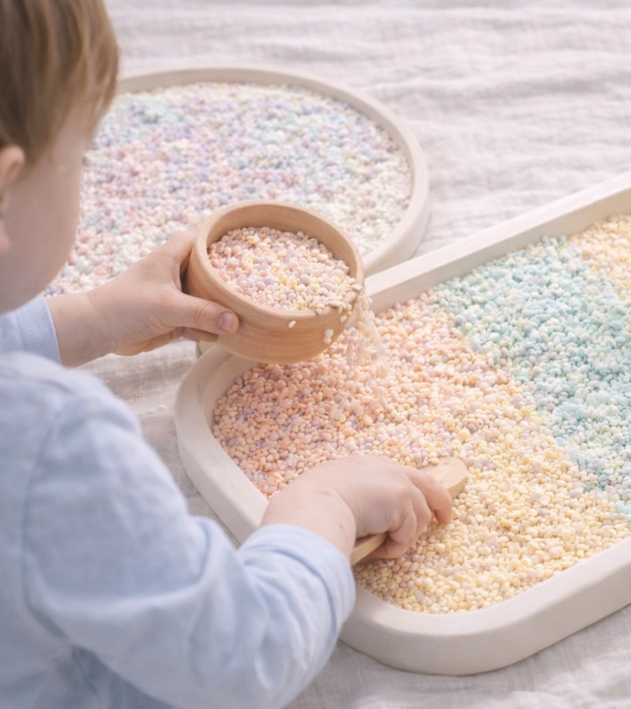 Ein Kind füllt bunte Zuckerperlen in eine Schale.