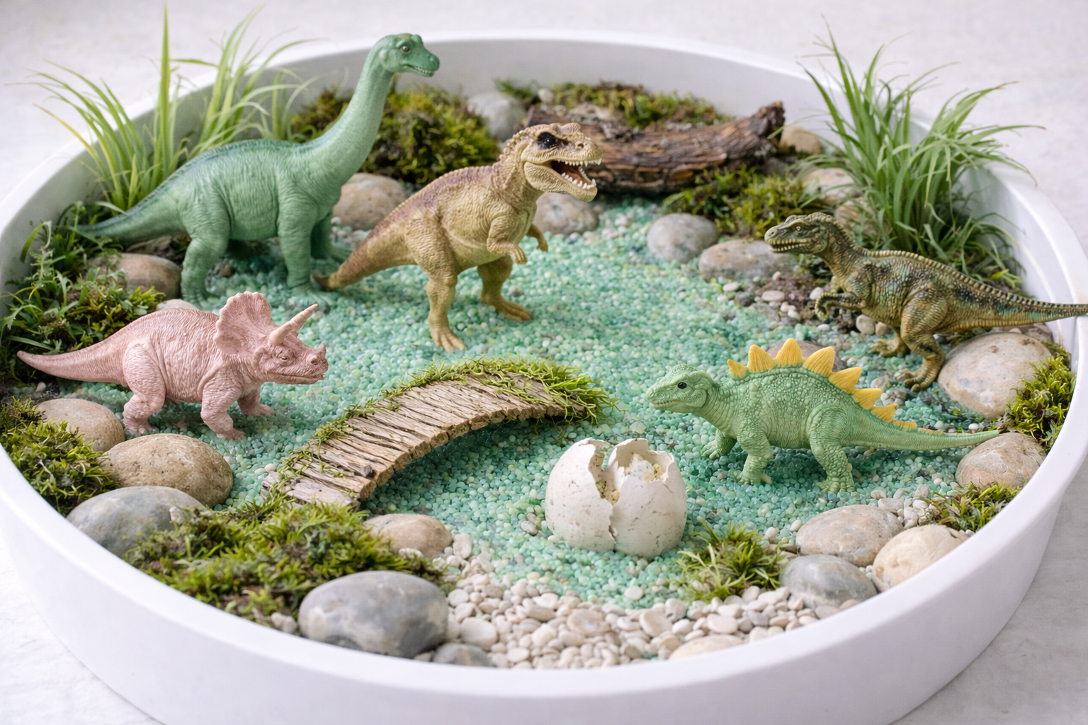 Kreisförmiges Spielset mit Spielzeug-Dinosauriern, Pflanzen, Steinen, einem Rückensteg und einem Ei.