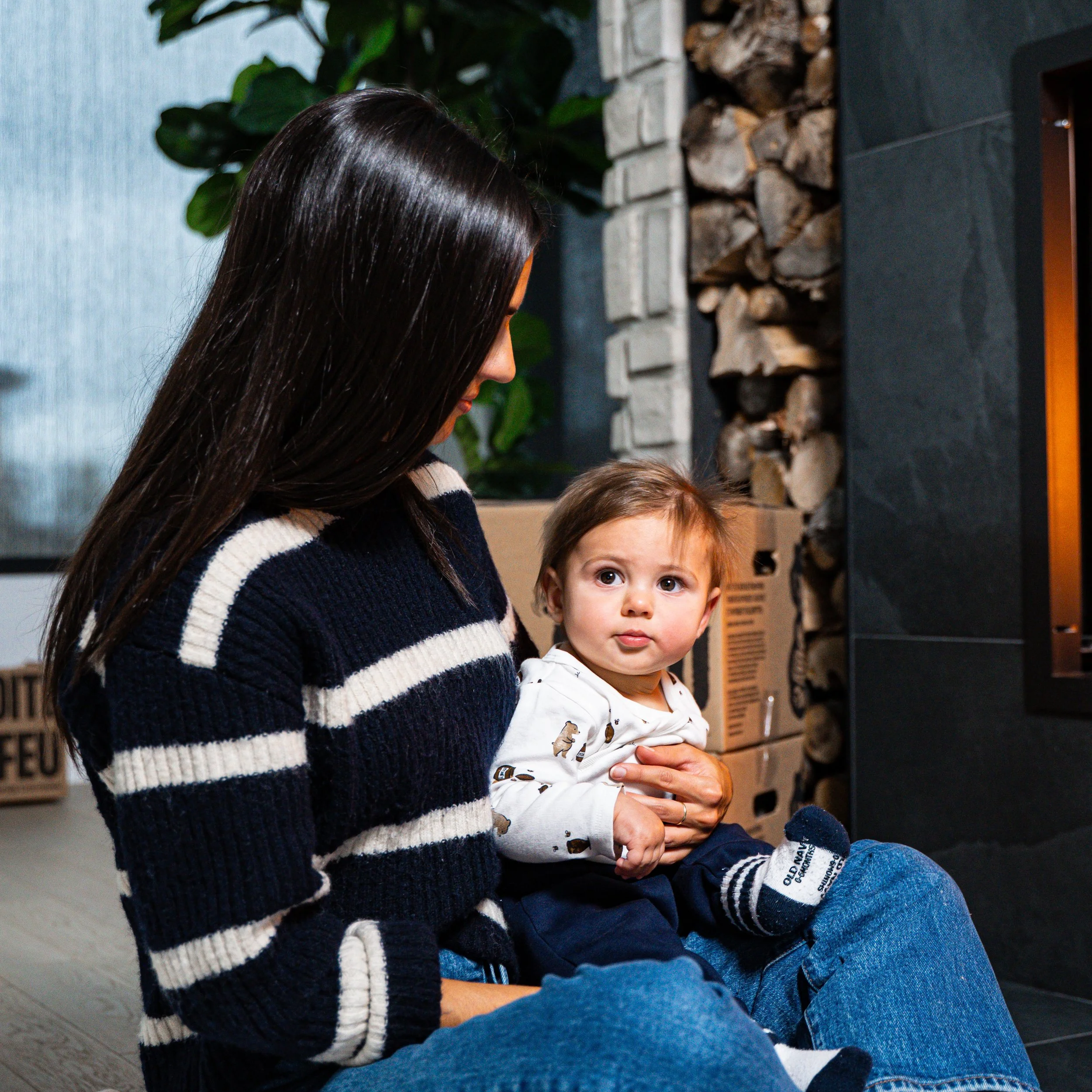 Une femme et un jeune enfant assis près d'une cheminée en pierre