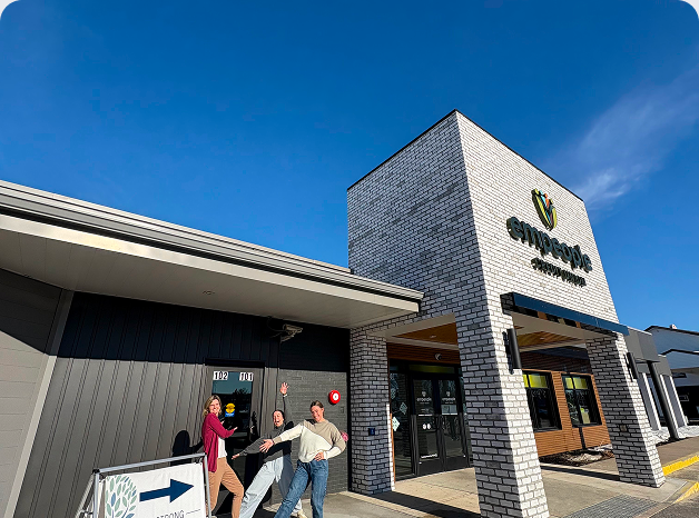 Group of four people standing outside a building with a sign that reads 'emergent' under a blue sky.