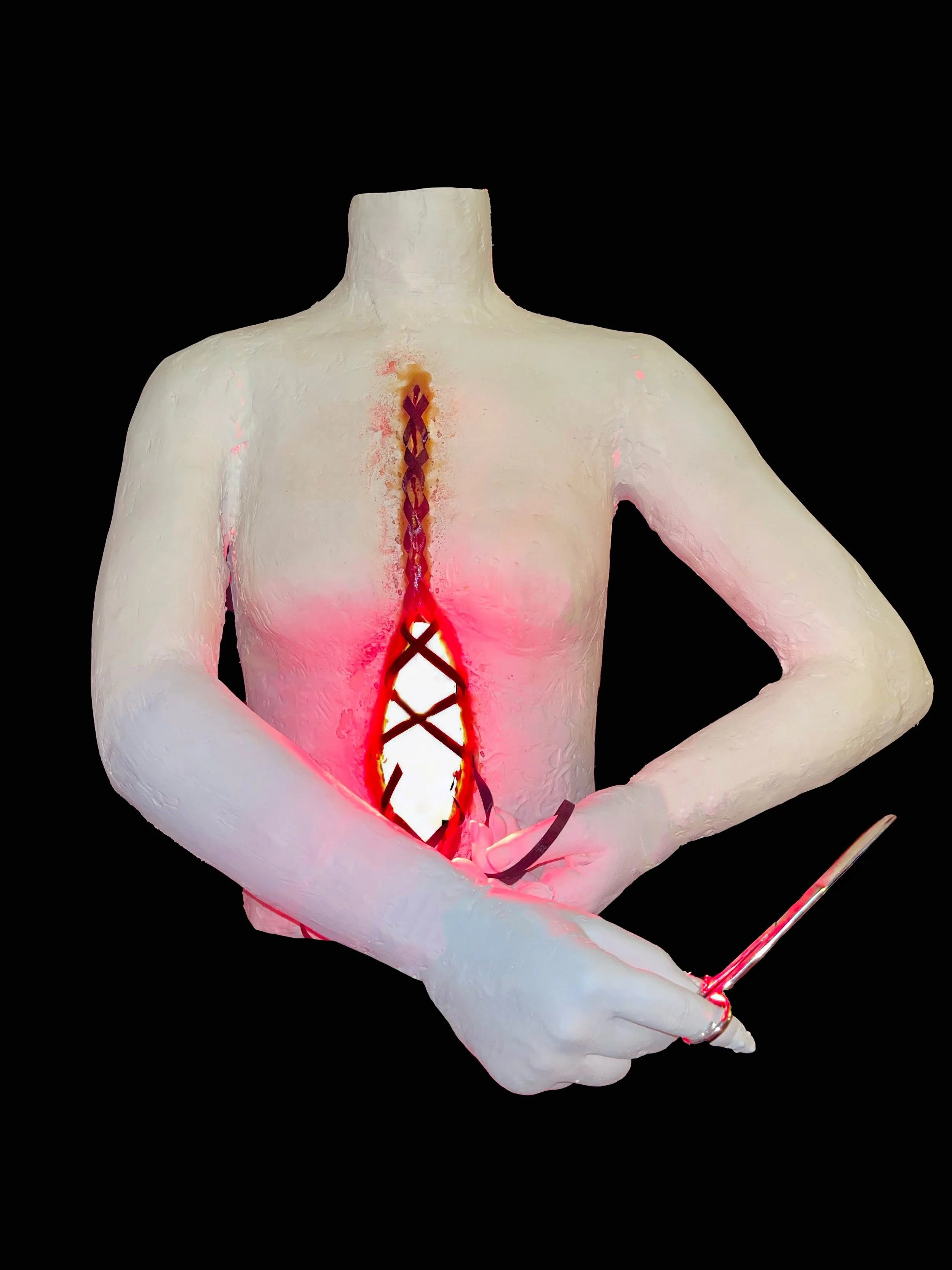 A sculpture of a human torso with a cutout section in the chest, illuminated with red light, and a hand holding a long, thin object.