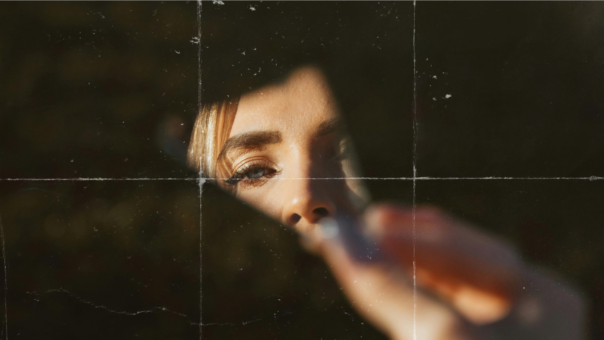 A woman gazing into a cut piece of mirror. Being seen vs. hiding