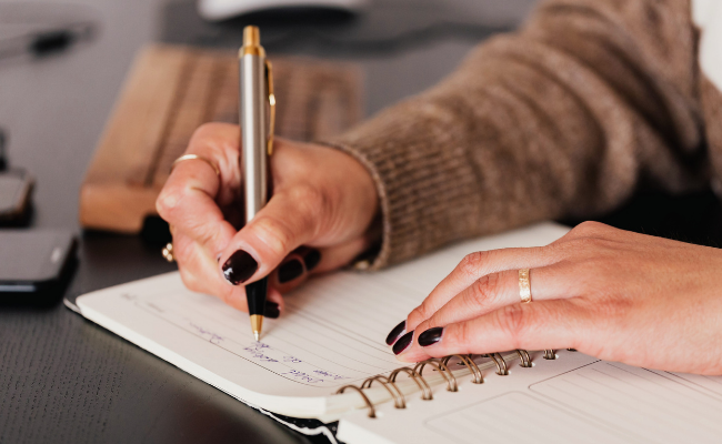 woman's hands writing in a journal