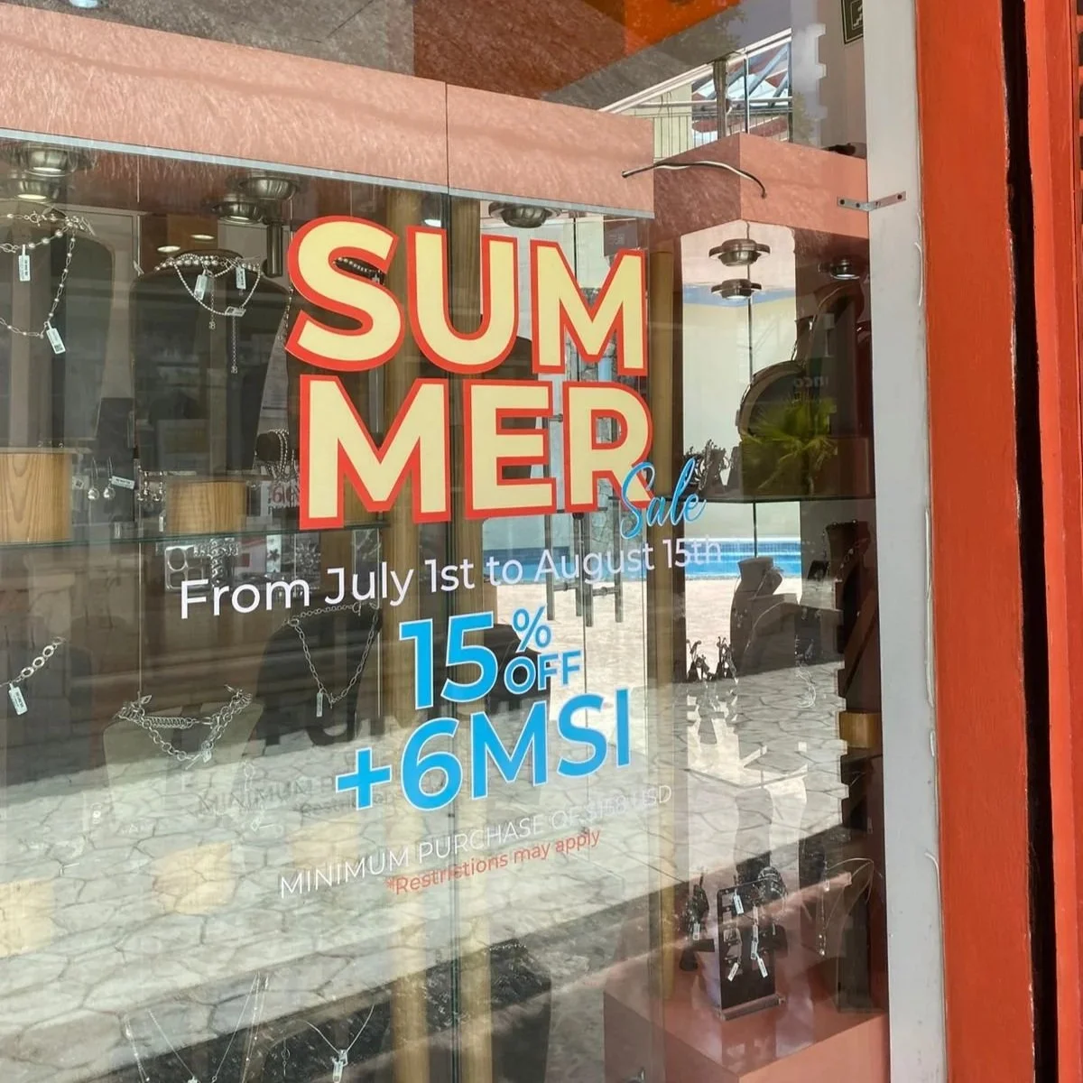 Cartel de venta en una tienda que anuncia una oferta de verano con 15% de descuento y 6 meses sin intereses, válida del 1 de julio al 15 de agosto.