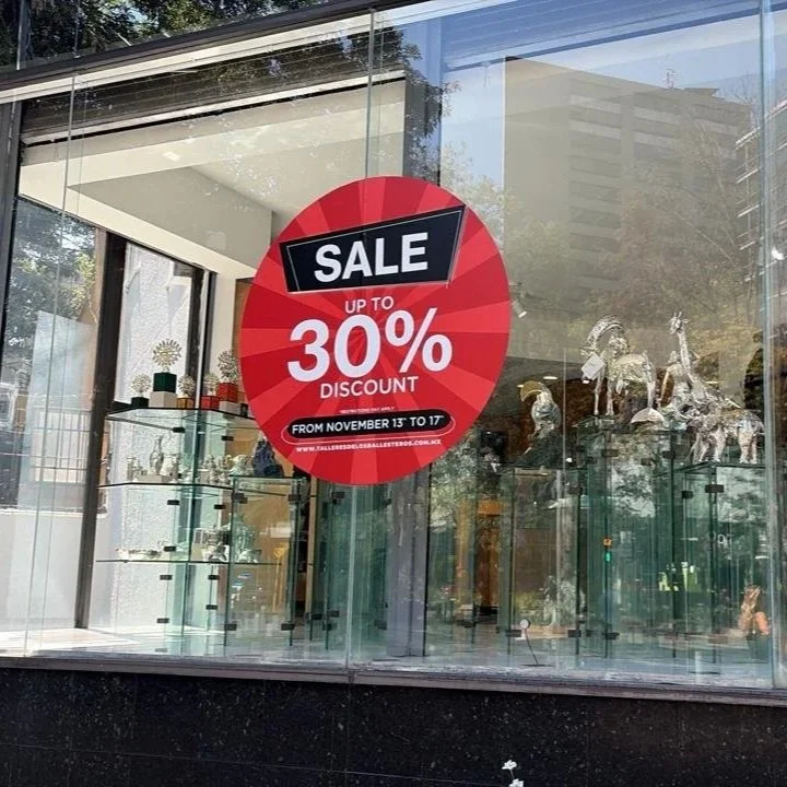 Publicidad en la ventana de una tienda ofreciendo una venta con hasta 30% de descuento, vigente del 13 al 17 de noviembre.