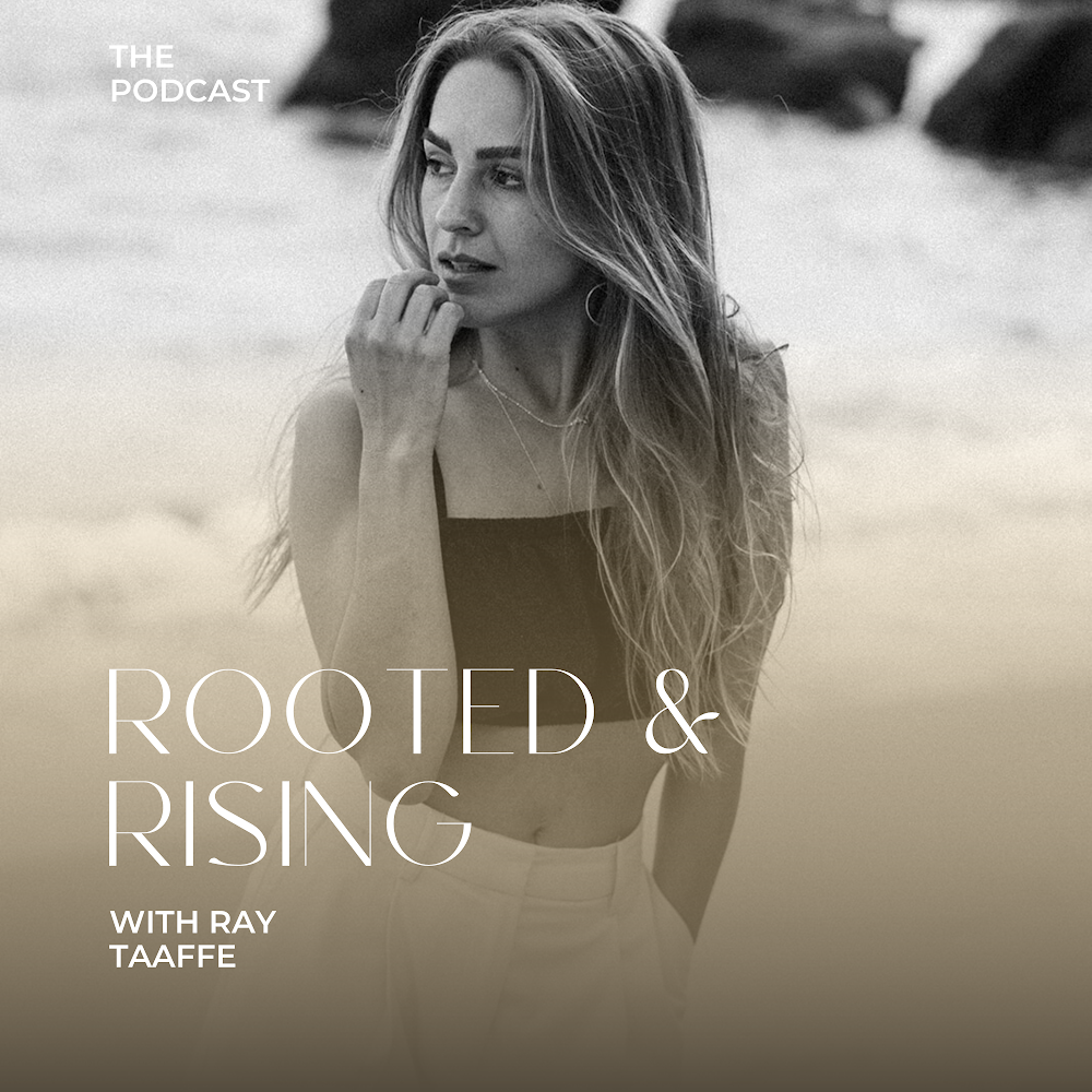 Black and white photo of a woman with long hair, wearing a sleeveless top, looking thoughtful on a beach with rocks in the background. Text on the image reads 'The Podcast' and 'Rooted & Rising with Ray Taaffe.'
