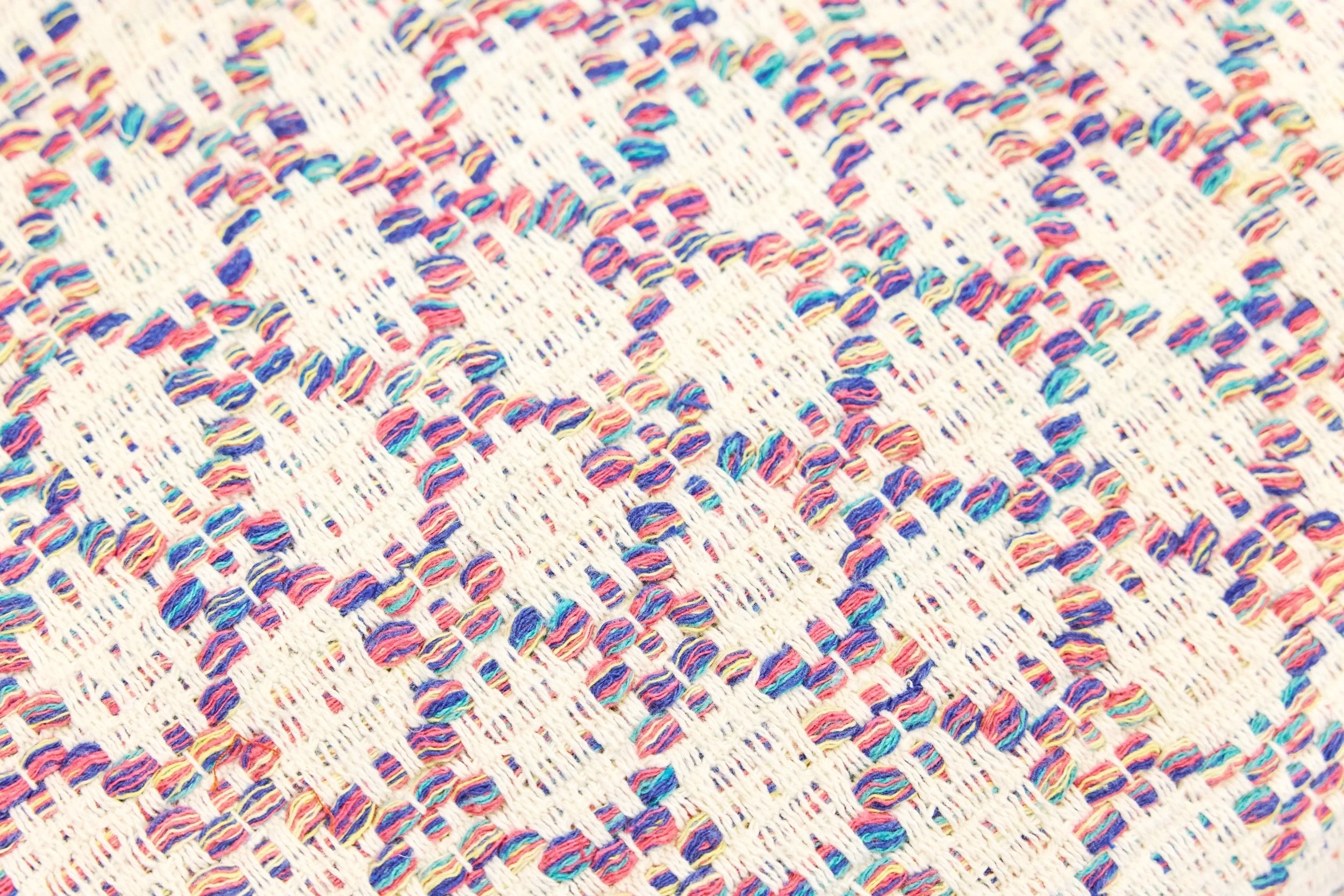 Close-up view of multicolored yarn woven into a fabric with a pattern of white bands.