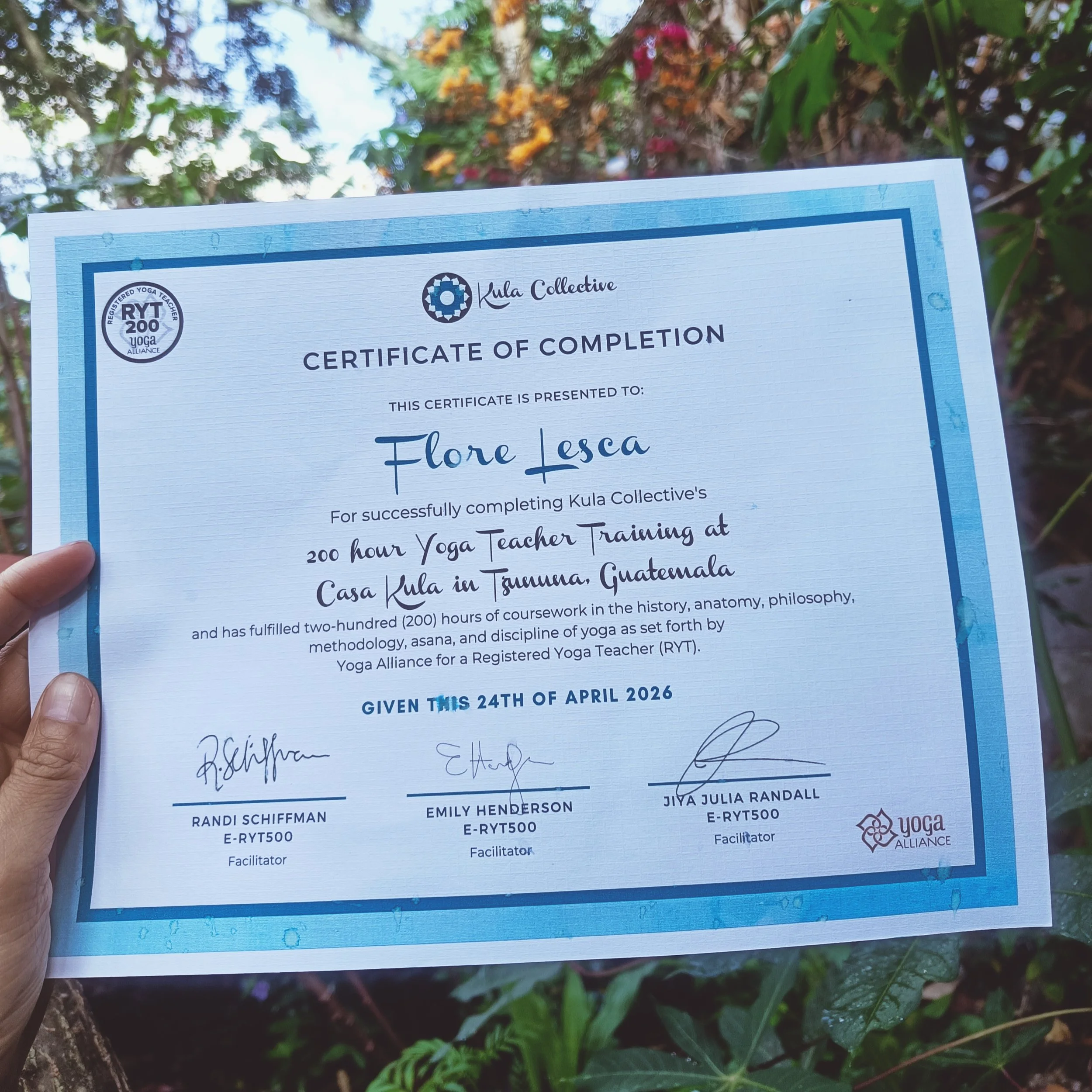 Close-up of a certificate of completion held by a person outdoors, with trees and foliage in the background.