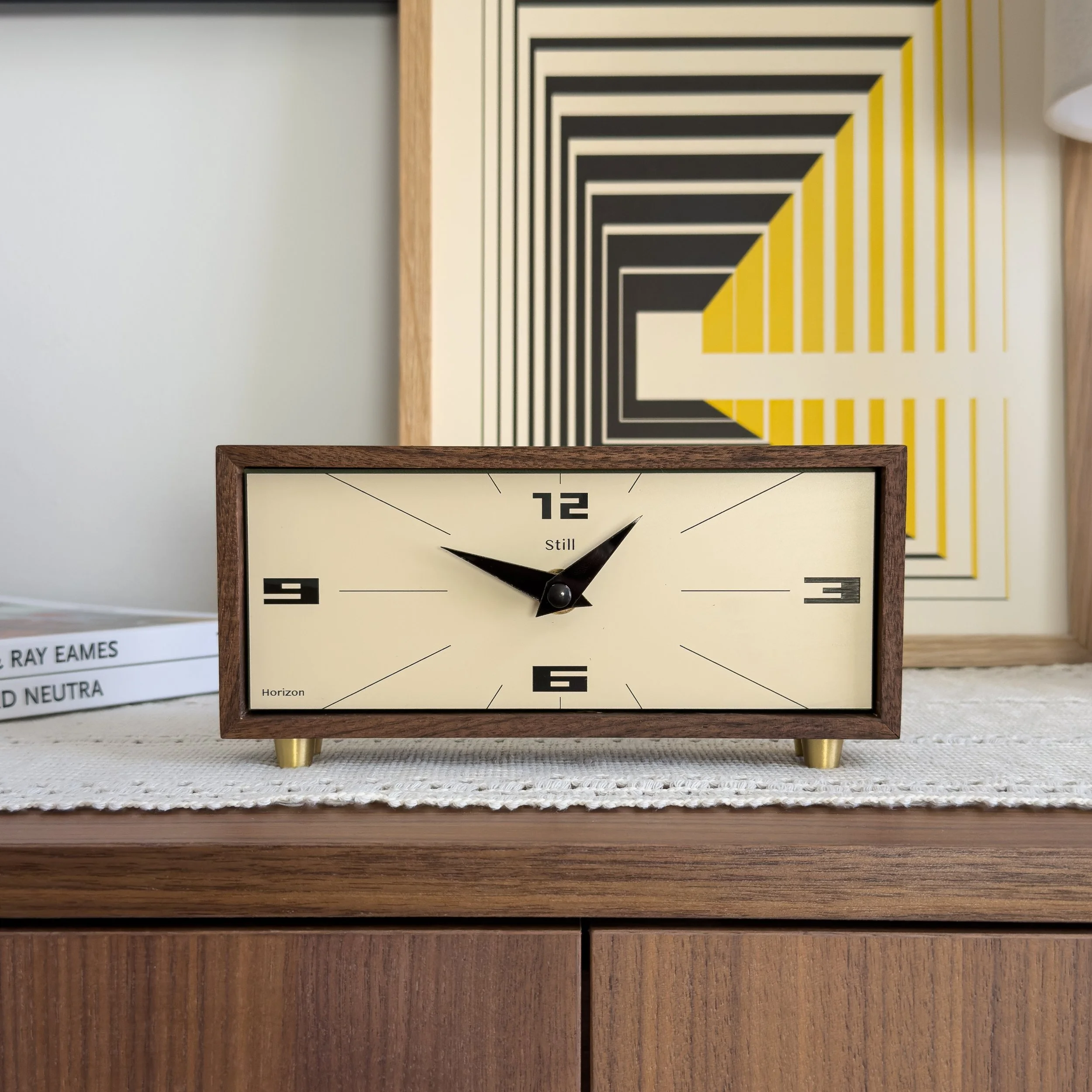Rectangular mid century modern walnut desk clock with cream face and minimalist markers styled on a wood console. Modern mantel clock with clean architectural lines and solid wood frame.