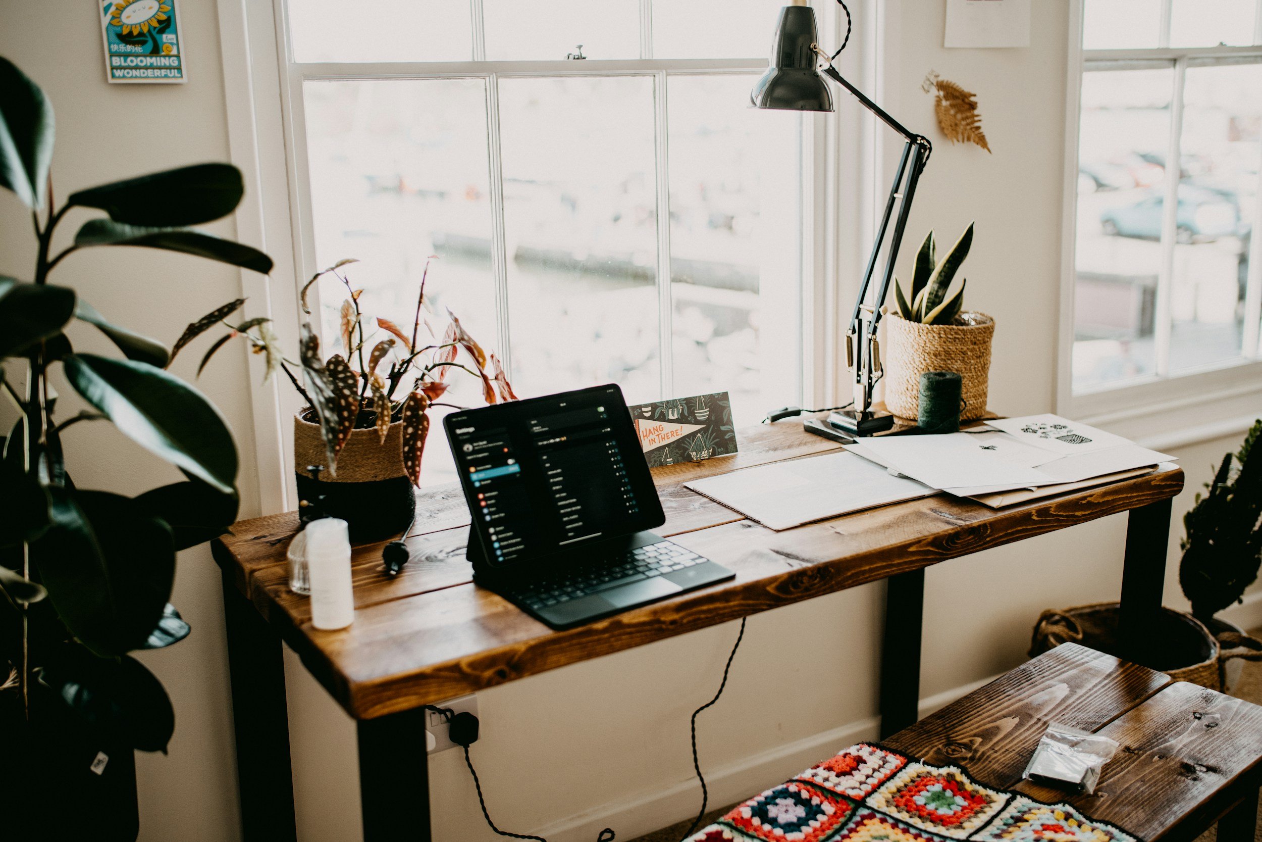 A cozy home office workspace with a wooden desk near a large window.