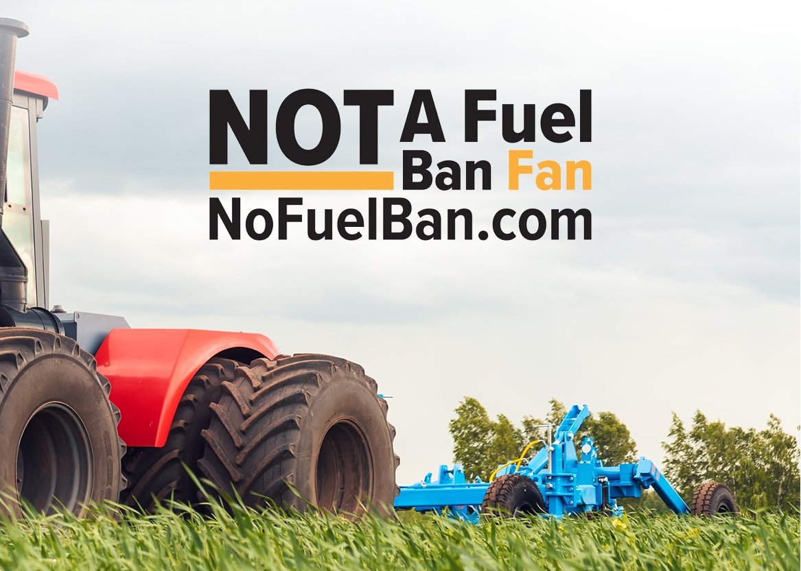 A tractor with large black tires in a field of green grass, with a blue piece of farming machinery in the background, and a sky with clouds. Text overlay says 'NOT A Fuel Ban Fan' and a website address 'NoFuelBan.com'.