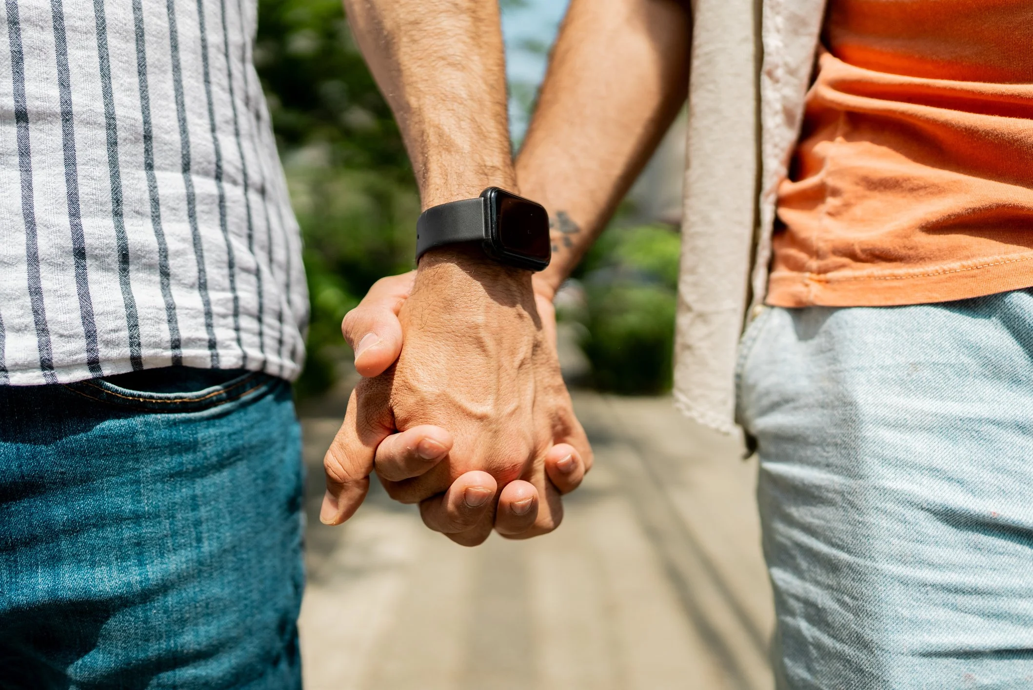 Close up of the hands of two people as they hold hands.