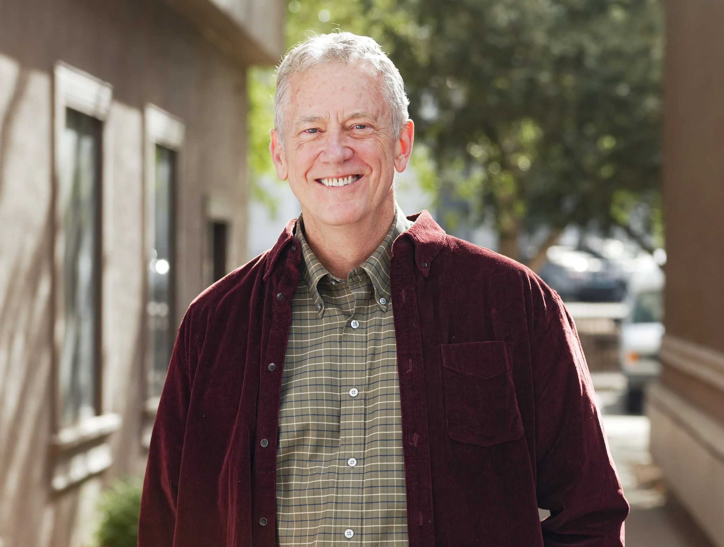 Dr. Gallant, a man with short graying hair, wears a plaid collared shirt and maroon jacket and smiles at us.
