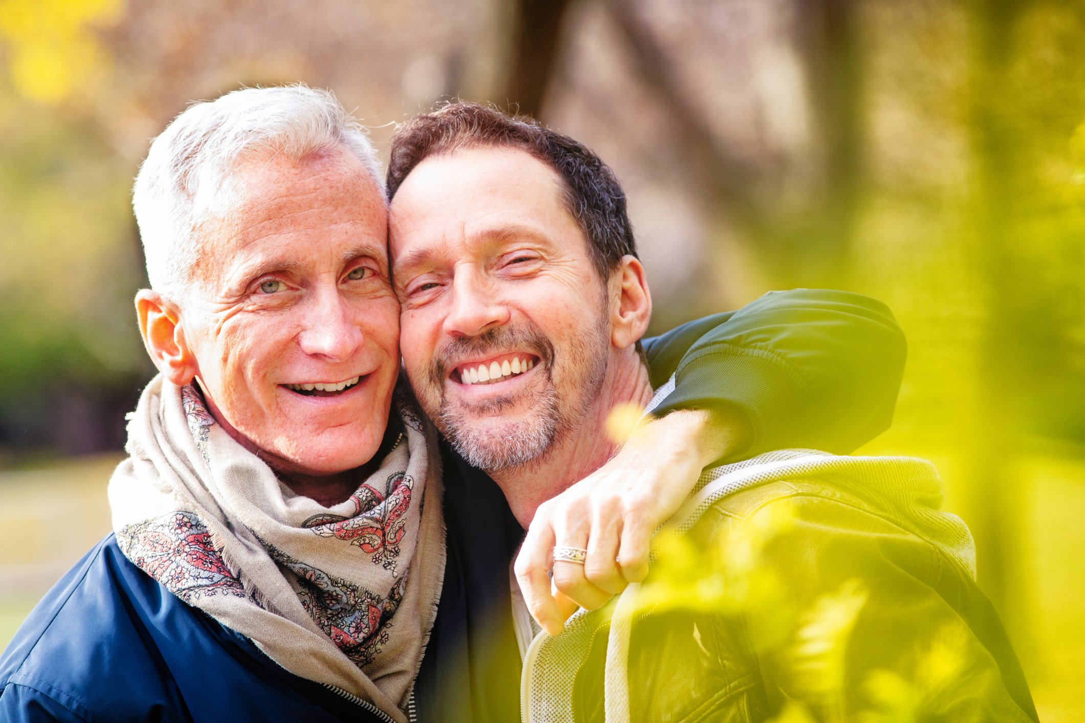 2 older white men side hug tightly as they smile exuberantly.