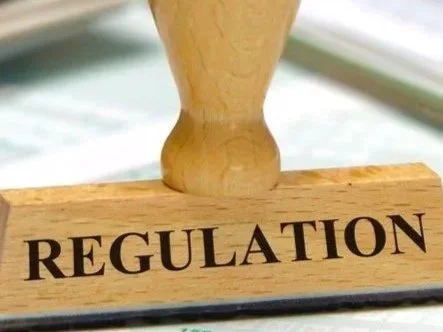 Close-up of a wooden stamp with the word 'REGULATION' pressed into it.