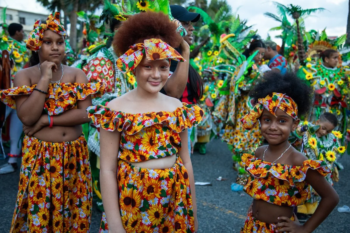 Children wearing colorful sunflower-themed costumes participating in a cultural parade or festival.
