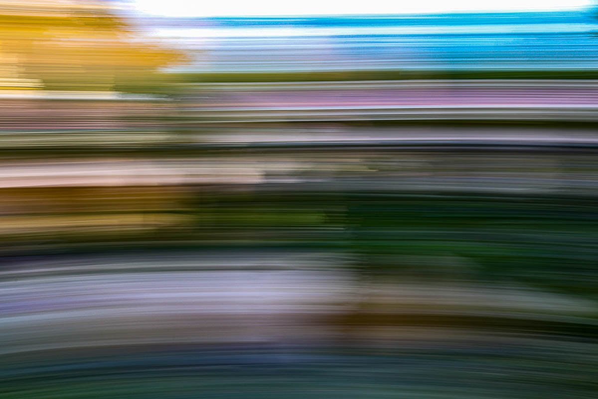 Abstract blurred landscape with horizontal streaks of various colors including green, brown, blue, and purple.