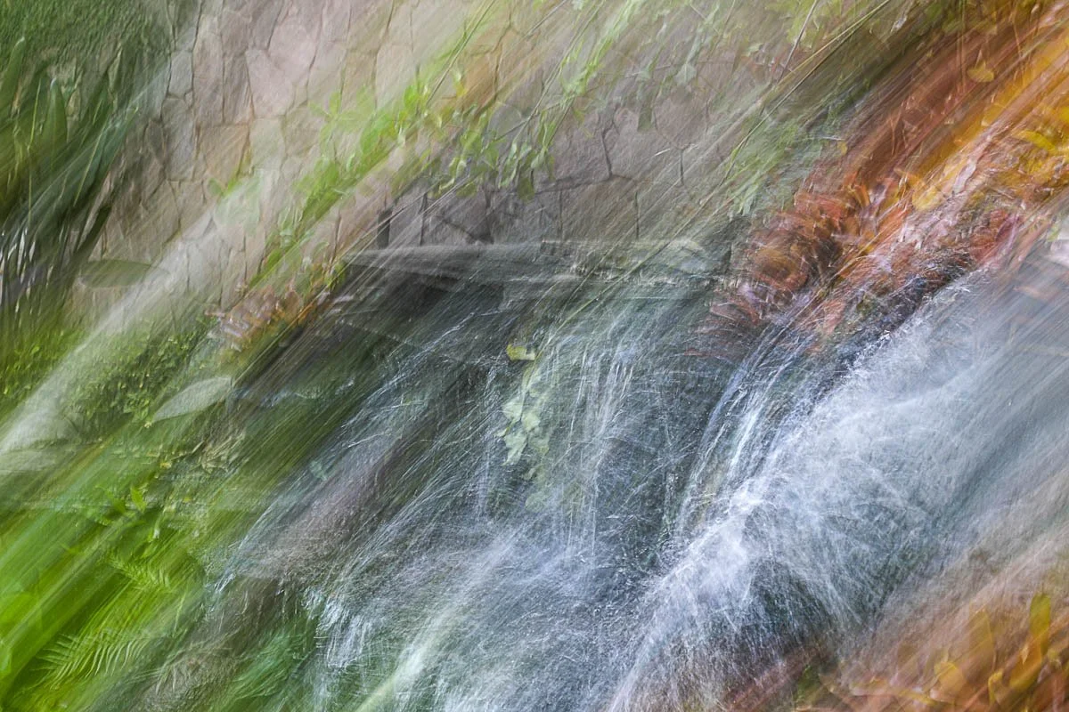 A small waterfall flowing over rocks surrounded by lush greenery.