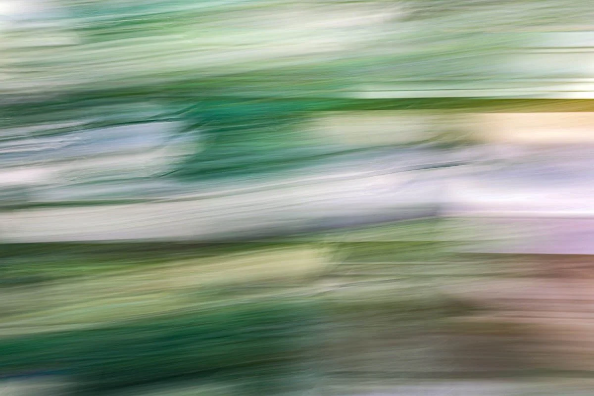 Blurry abstract image with green, white, and purple streaks.