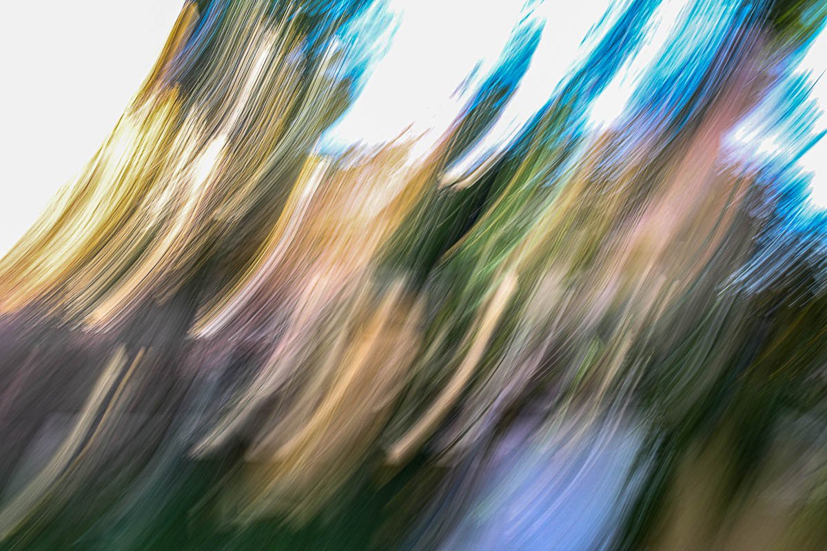 Abstract streaks of various colors, resembling a motion-blur effect, with shades of yellow, green, blue, purple, and brown.
