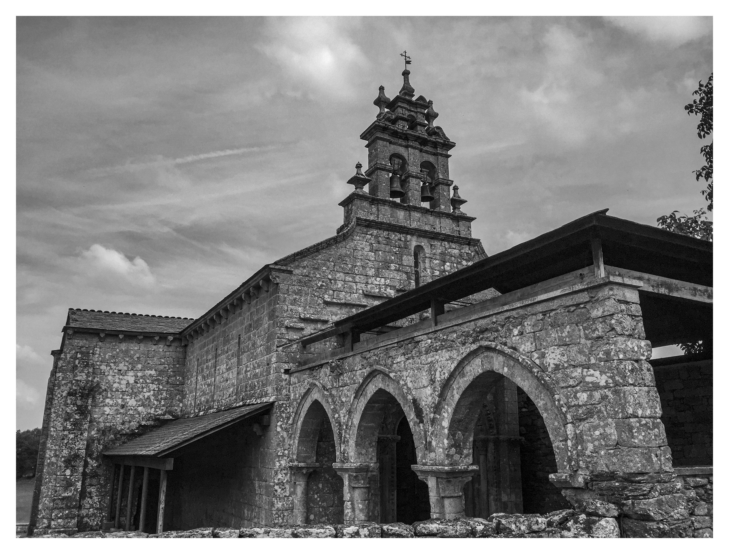 Historic stone church with bell tower and arched entrance, black and white photo.
