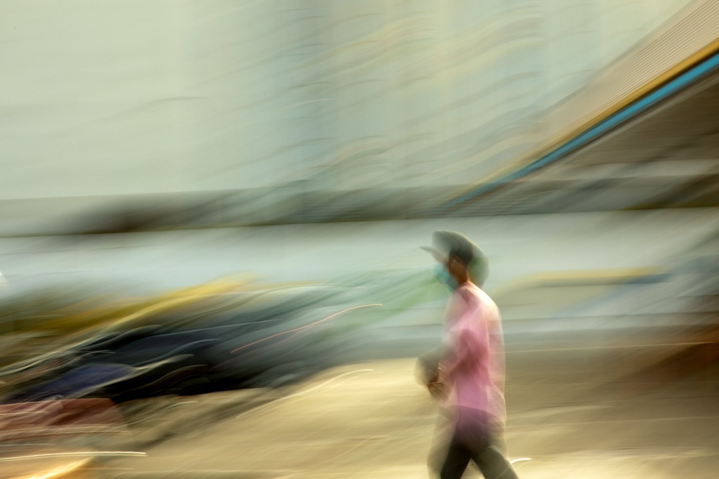 A person wearing a cowboy hat and pink shirt walking.