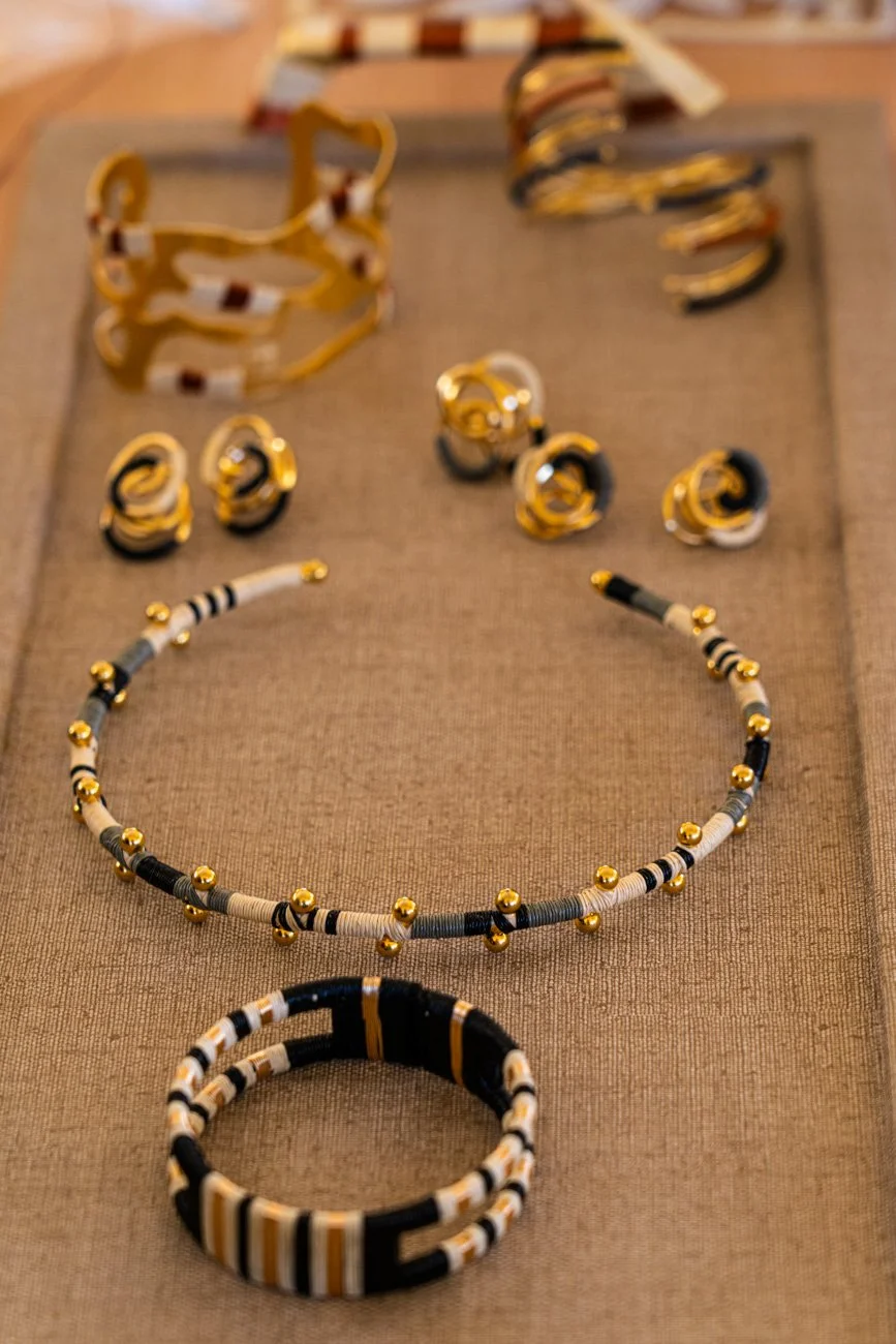 Assorted gold and black jewelry, including bracelets, earrings, and a necklace, displayed on a fabric surface.