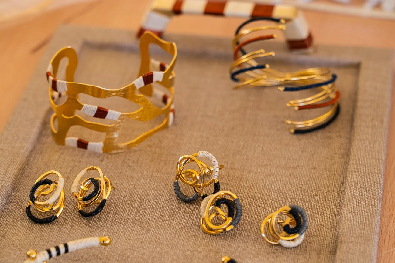 Collection of gold and black jewelry including bangles, earrings, and a cuff bracelet displayed on a fabric surface.