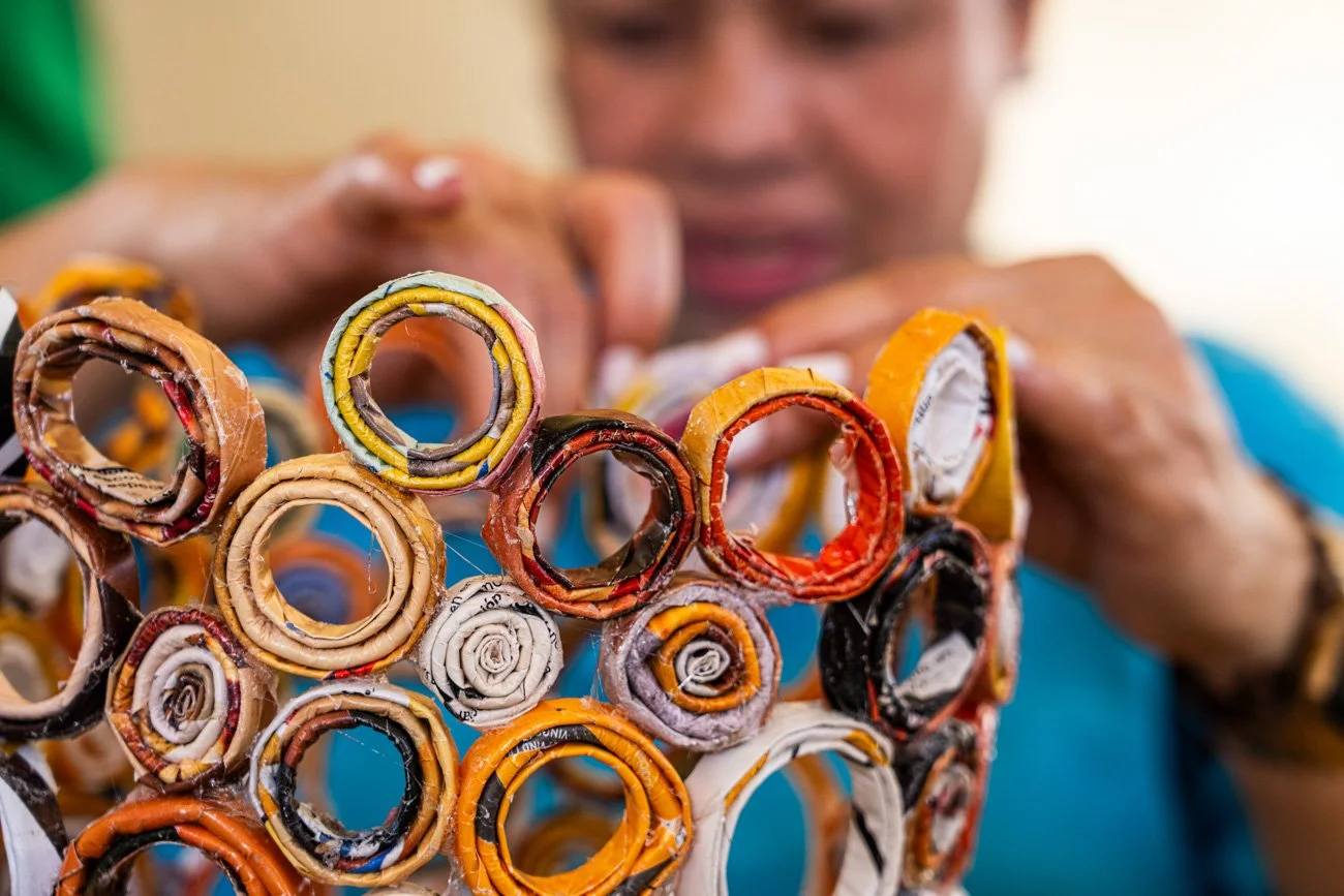 Person holding a sculpture made from tightly rolled and layered recycled paper rings.
