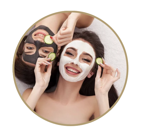 Two women with facial masks lying down, holding cucumber slices to their eyes, and smiling.