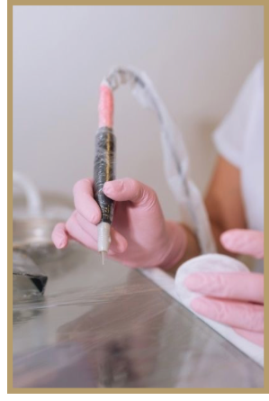 Person holding a device with a pink tip, possibly a medical or beauty tool, over a table.