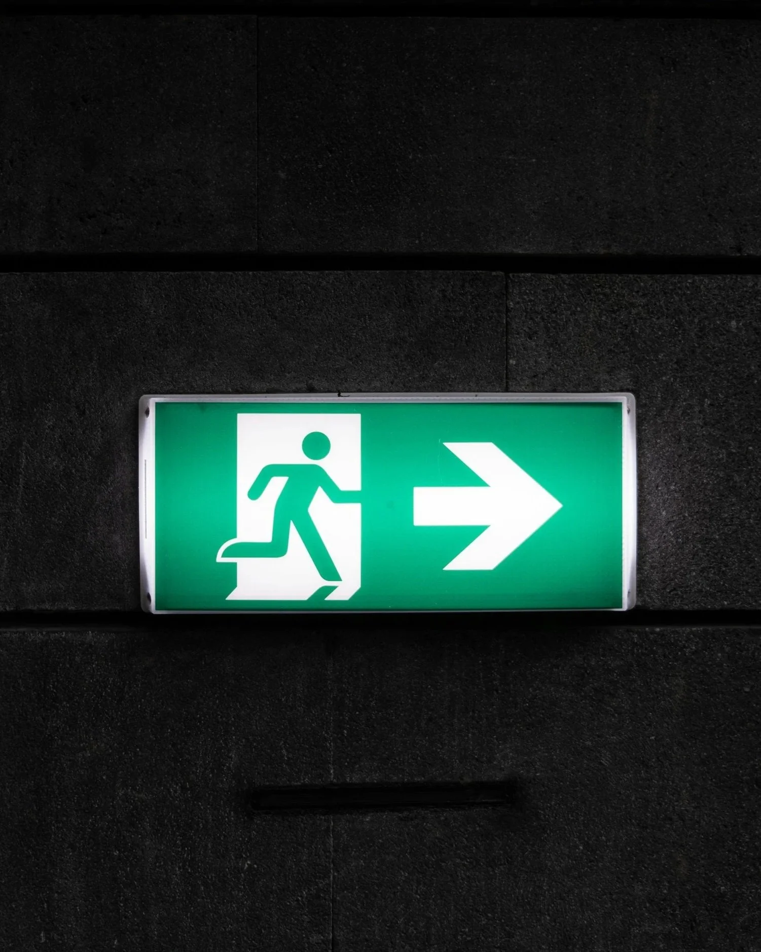Green emergency exit sign with running figure and right arrow