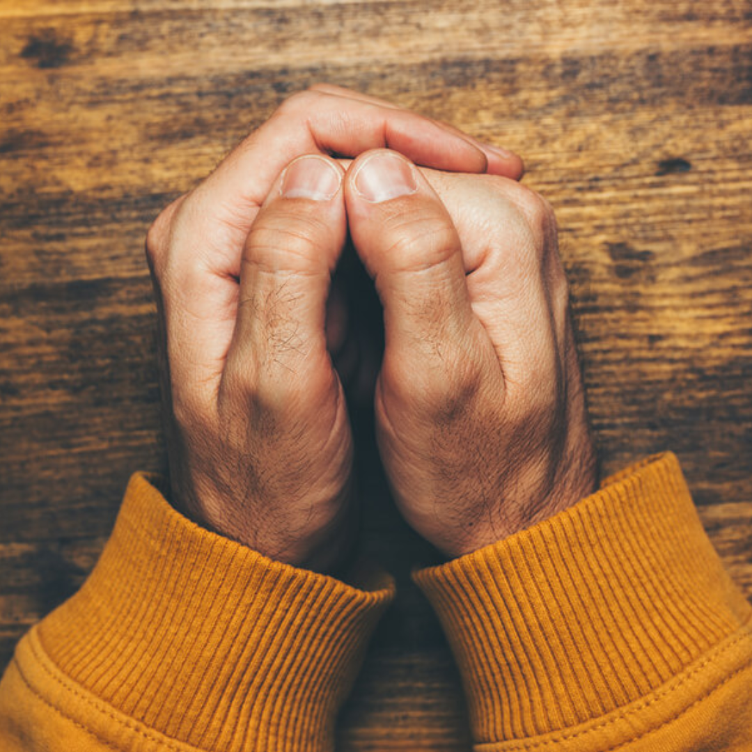 Man's hands clasped in reflection, representing men's counseling and spiritual trauma recovery in Charlotte, NC
