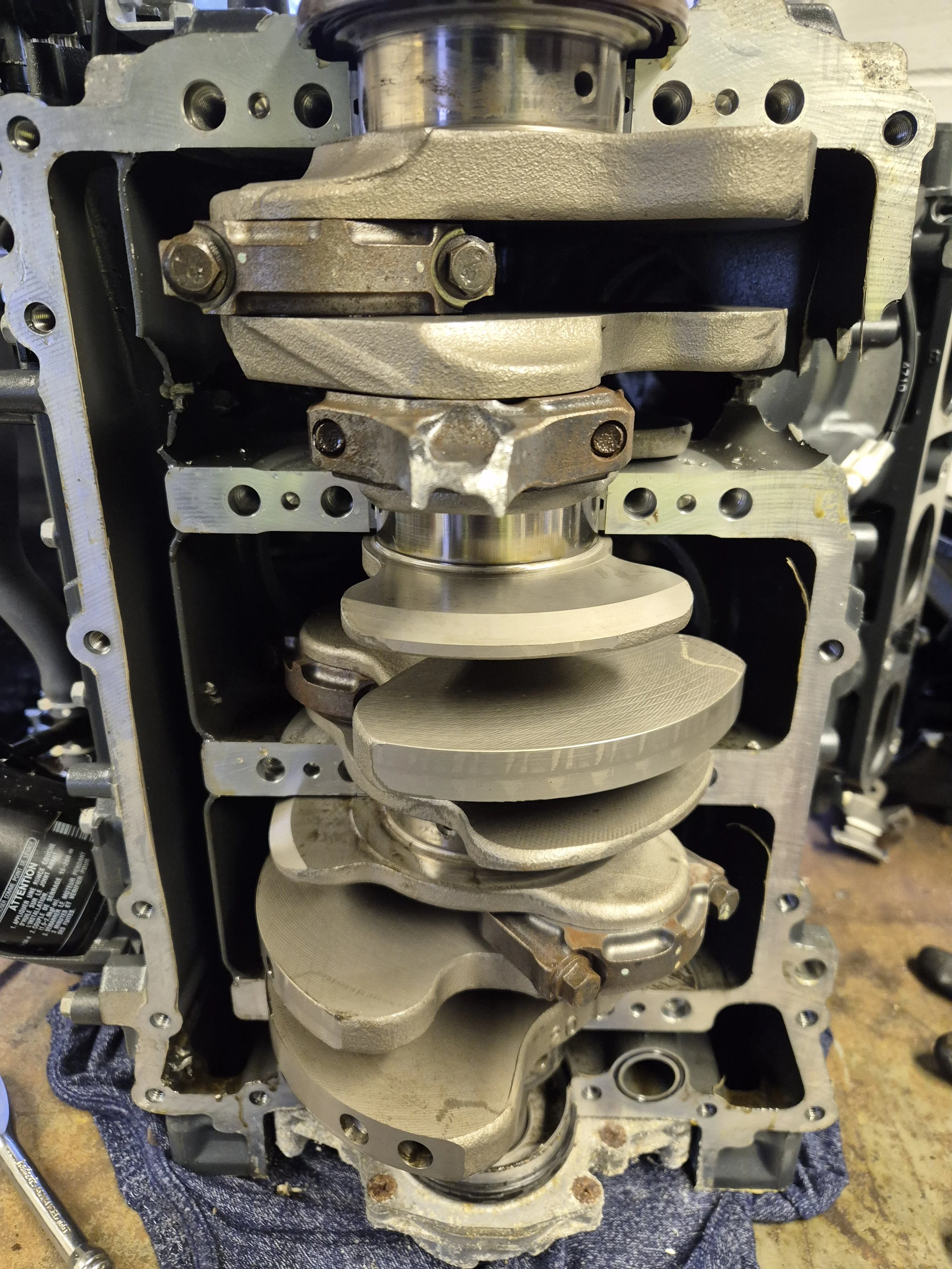 Close-up view of an internal engine component, showing the crankshaft, connecting rods, and pistons inside an engine block.